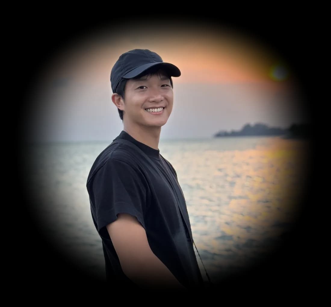 Joel smiling by the sea at sunset